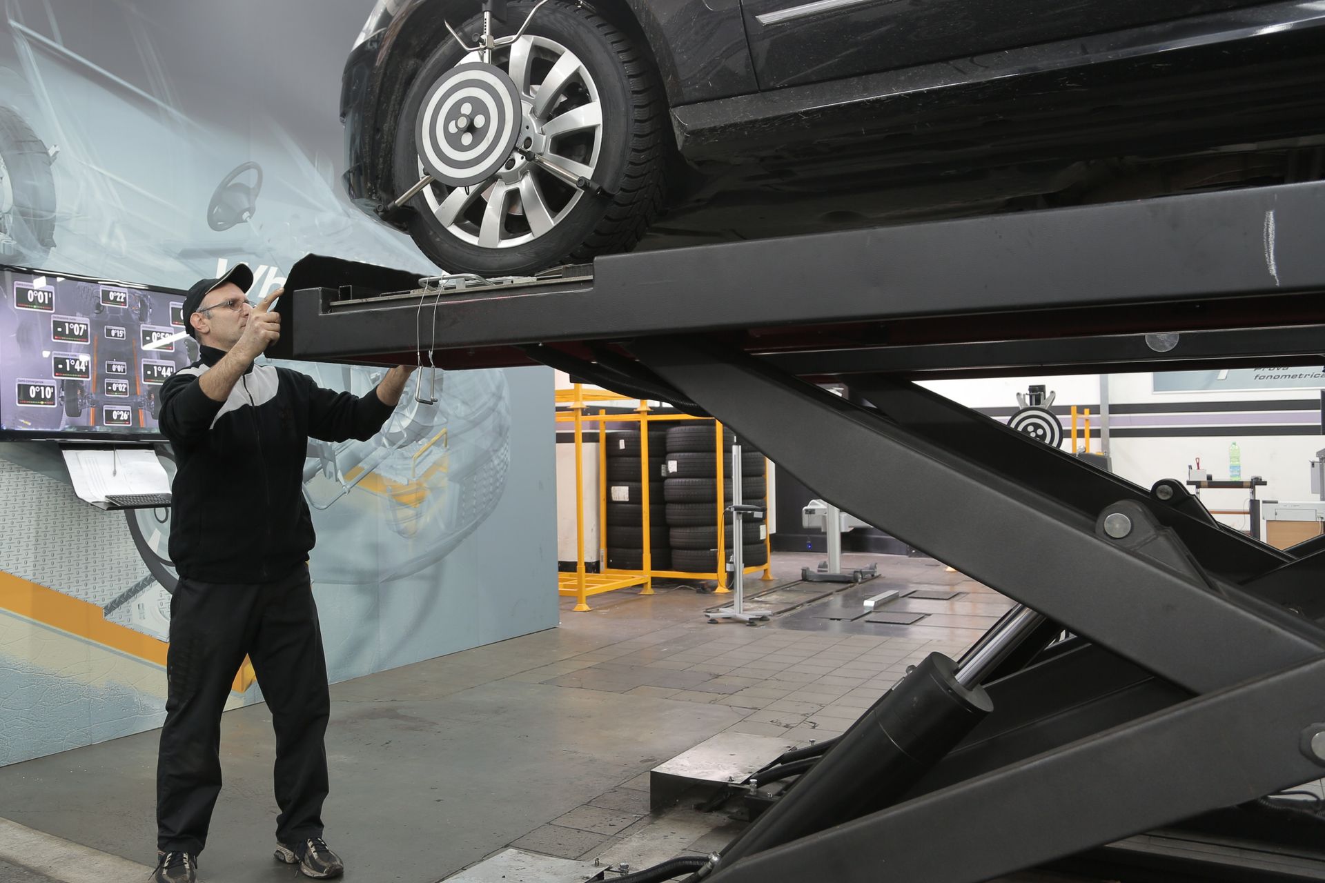 Mechanic inspecting a car on a ramp in a busy car service garage