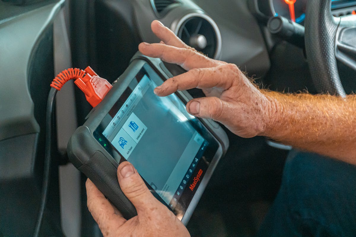A technician using a diagnostic scanner on a car